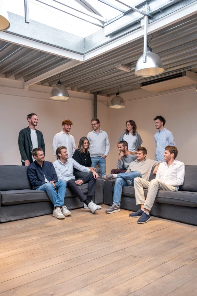 Membres de l'équipe de la startup Fline réunis dans un espace de travail convivial, discutant assis sur des canapés sous une verrière